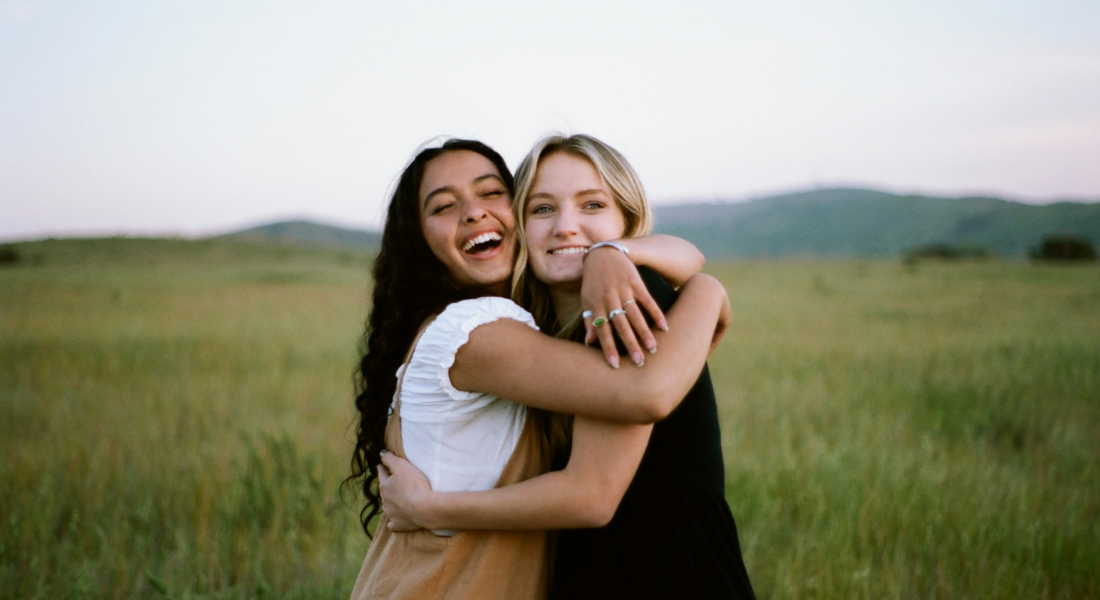 two women hugging in a field