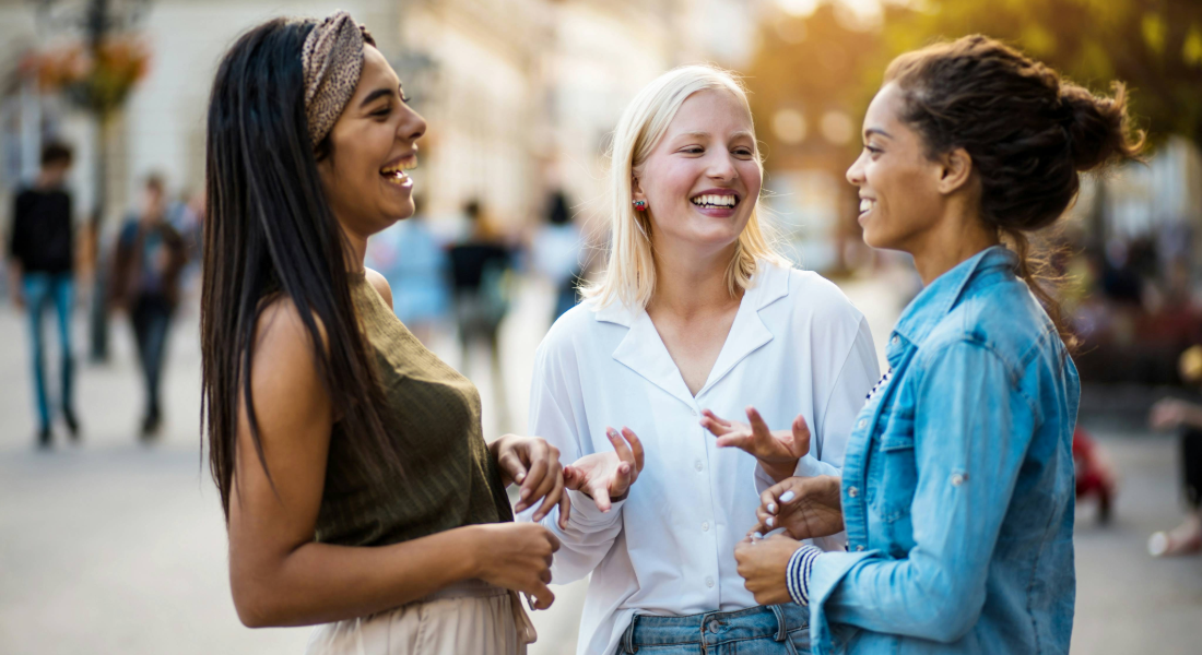 three women talking and laughing on the street