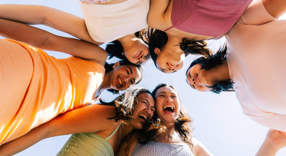 6 women in a circle laughing